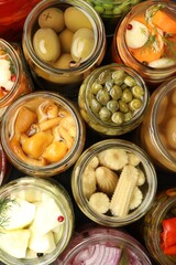 Different pickled products in jars on table, top view