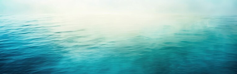 The image shows a tranquil scene of a blue water surface with a soft layer of fog. The water ripples gently, and the fog creates a hazy, ethereal effect. The morning light casts a pale, luminous glow 