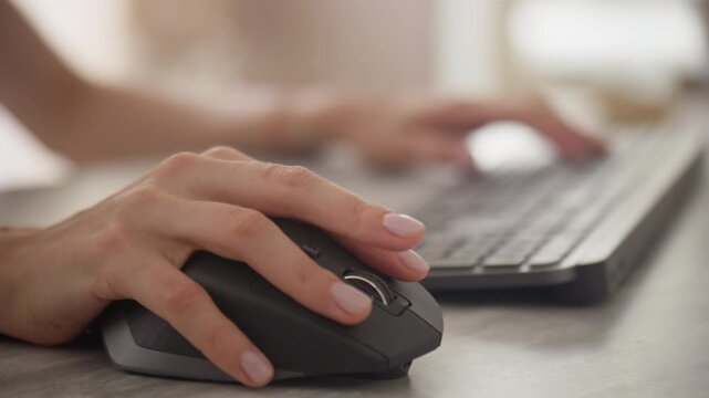 Close-up of hands using a mouse and typing on a keyboard