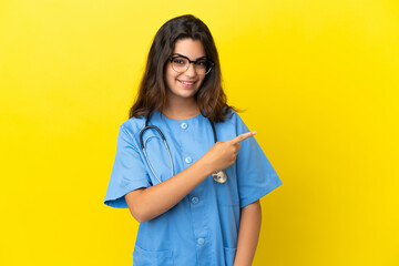 Young surgeon doctor woman isolated on yellow background pointing to the side to present a product