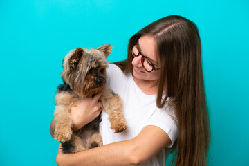 Young Lithuanian woman holding a dog isolated on blue background