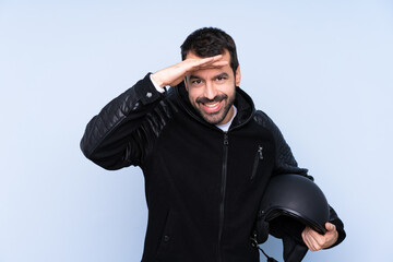 Man with a motorcycle helmet over isolated background looking far away with hand to look something