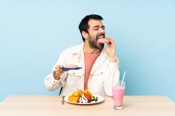 Man at a table having breakfast waffles and a milkshake