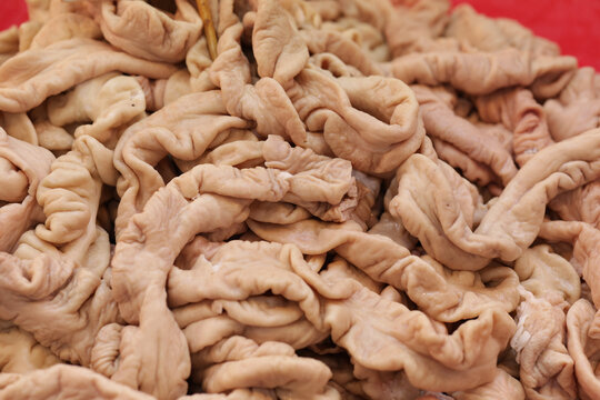 A lot of pork sausages are sold at the market. Fresh pork intestines are piled up on the table.