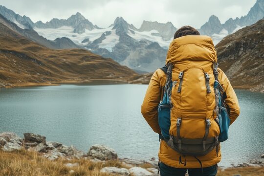 Backpacker standing by a mountain lake. The image can be used for travel blogs, articles, or social media posts about hiking and outdoor adventures.