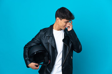 Young man with a motorcycle helmet over isolated blue background laughing