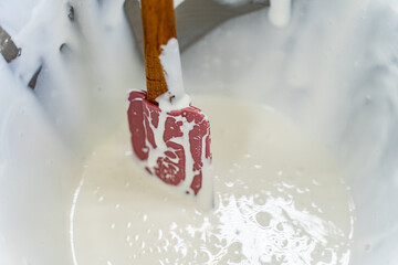 The process of making dough in production. A large container with batter is mixed with a spatula