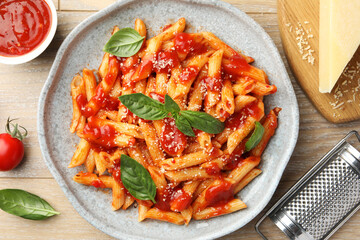 Delicious pasta with tomato sauce, basil and cheese on wooden table, flat lay