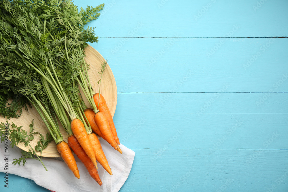 Wall mural Tasty ripe juicy carrots on light blue wooden table, flat lay. Space for text