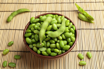 Raw green edamame soybeans and pods on wicker mat