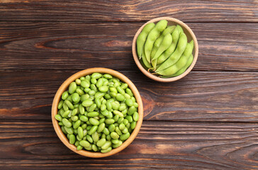 Raw green edamame soybeans and pods on wooden table, top view