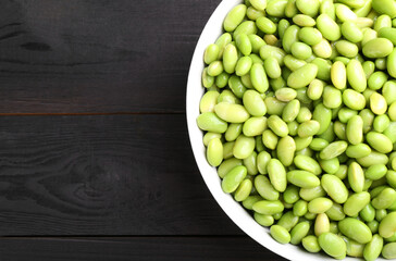 Raw green edamame soybeans on wooden table, top view. Space for text