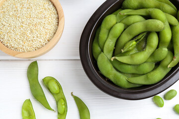 Fresh edamame pods, soybeans and seeds on white wooden table, flat lay