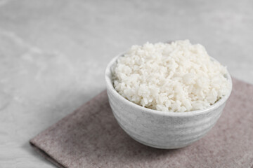 Delicious boiled rice in bowl on grey table. Space for text