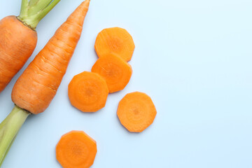 Whole and cut fresh carrots on light background, flat lay. Space for text