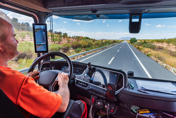 From inside the cab of a truck, driver holding the steering wheel firmly while driving on a...
