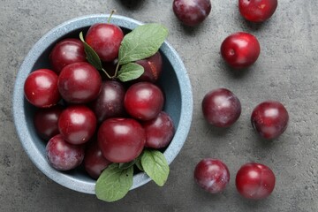 Fresh plums on grey textured table, flat lay