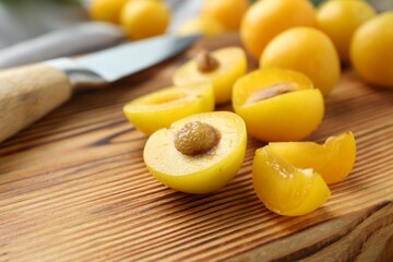 Whole and cut ripe plums on wooden table, closeup