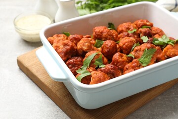 Baked cauliflower buffalo wings with parsley in baking dish on grey table, closeup