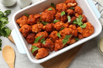 Baked cauliflower buffalo wings with parsley served on grey textured table, flat lay