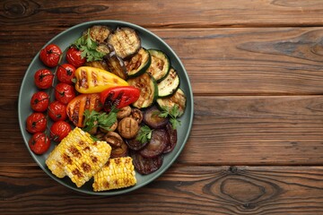 Delicious grilled vegetables on wooden table, top view. Space for text