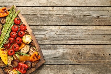 Delicious grilled vegetables on wooden table, top view. Space for text