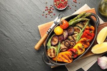 Delicious grilled vegetables in baking dish served on grey textured table, flat lay. Space for text