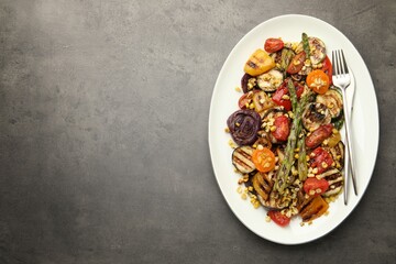 Delicious salad with grilled vegetables served on gray textured table, top view. Space for text