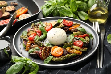 Tasty salad with grilled vegetables and mozzarella cheese served on black table