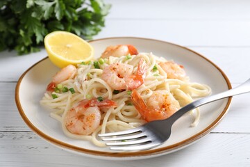 Delicious pasta with shrimps, green onion and fork on white wooden table, closeup