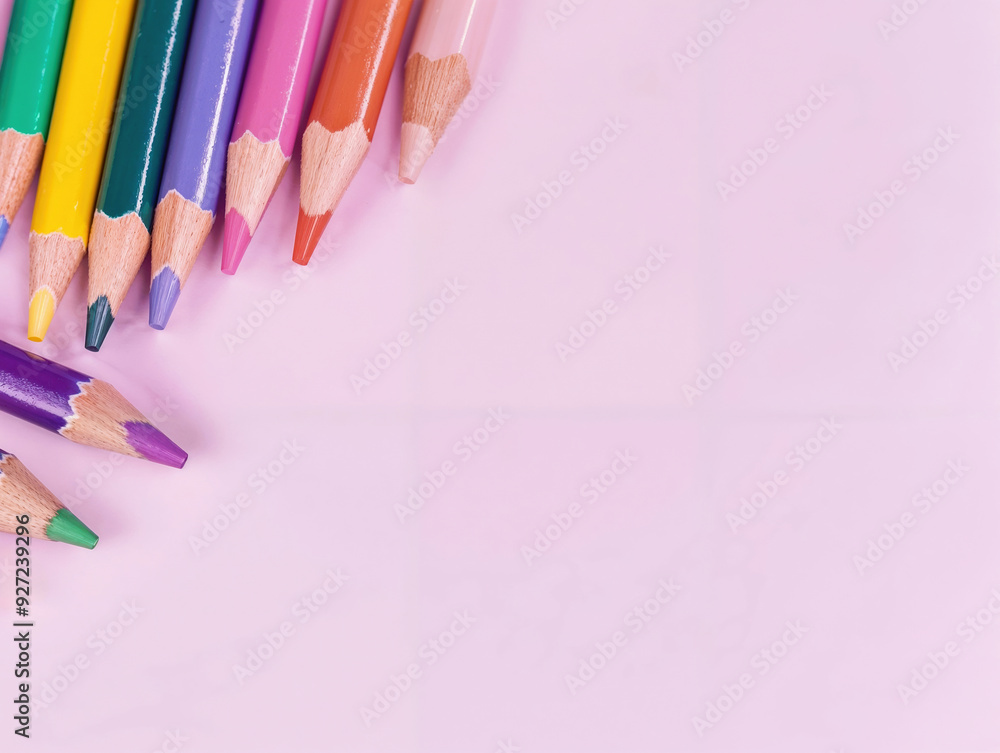 Poster set of colored pencils is arranged on a pink surface, creating a colorful and vibrant composition wi