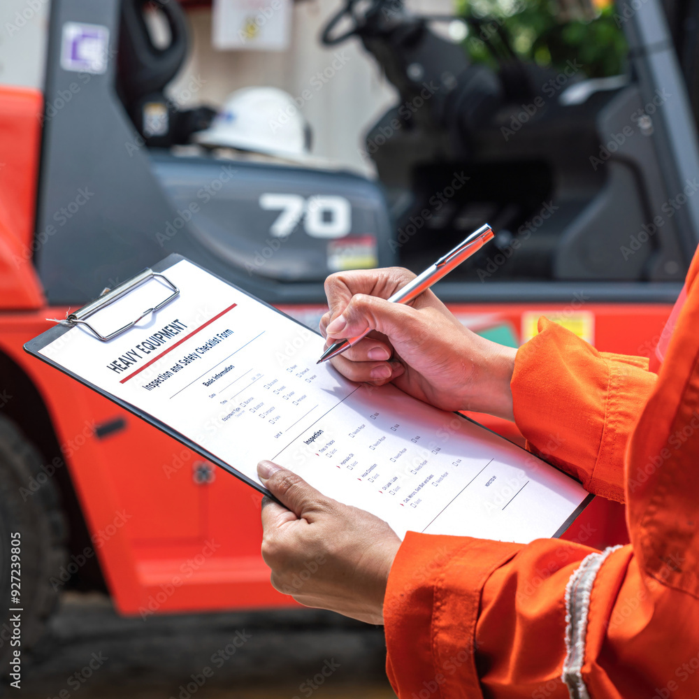 Wall mural a mechanical engineer is using heavy equipment checklist form for inspecting the factory forklift ve