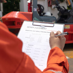 A mechanical engineer is using heavy equipment checklist form for inspecting the factory forklift...