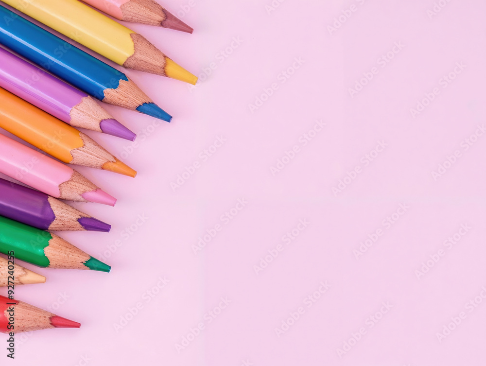 Poster row of colored pencils forming a diagonal line on a pink background with copy space
