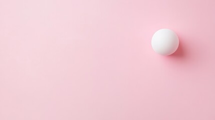 A simple white ball on a soft pink background, emphasizing minimalism and color contrast.