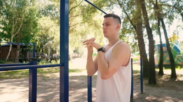 Handsome pumped up young male bodybuilder doing exercises on horizontal bar and parallel bars outdoors on the street. Beautiful male body shapes, beauty and health, training and motivation