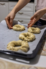 Baker put round dough for bagels in tray. Homemade preparation on bagel dough in kitchen. 