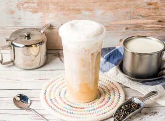 Iced Tieguanyin with Fresh Milk Tea or Tie guan yin with sugar pot and spoon served in disposable glass isolated on table side view of hong kong tea