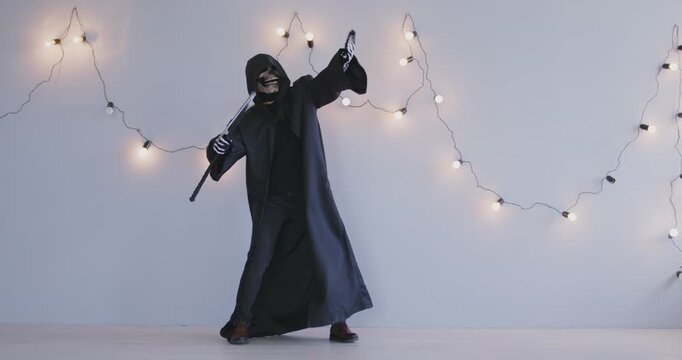 Funny scary Halloween Grim Reaper horrific figure dance in cosplay black costume, Angel of Death harvesting souls with scythe, black hooded cape, mysterious atmosphere spooky gothic ball event dancing