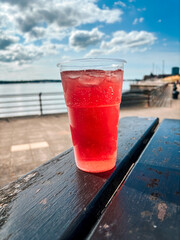 A plastic cup of fruit cider outside a pub on a summer afternoon. The River Mersey can be seen in the background