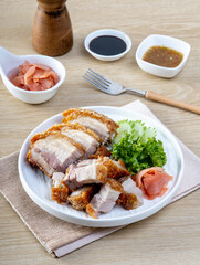 Crispy pork belly in a white plate on a wooden table