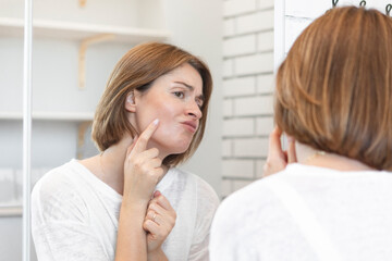 Young beautiful woman looking at mirror and confusing because of new wrinkles	