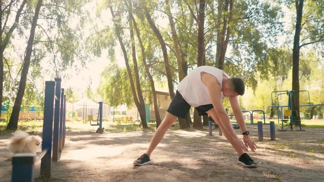 Handsome pumped up young male bodybuilder doing exercises on horizontal bar and parallel bars outdoors on the street. Beautiful male body shapes, beauty and health, training and motivation