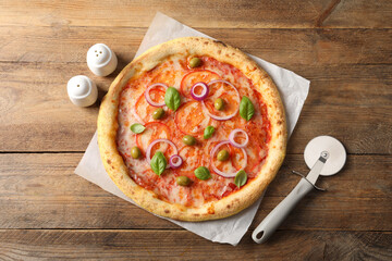 Delicious vegetarian pizza and cutter on wooden table, top view