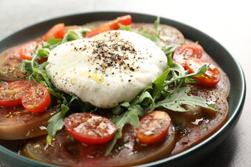 Delicious fresh burrata salad in bowl on gray table, closeup