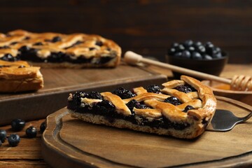 Piece of tasty homemade pie with blueberries served on wooden table, closeup