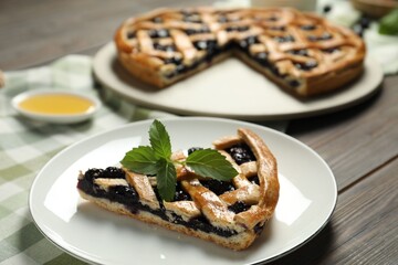 Piece of tasty homemade pie with blueberries and mint on table, closeup