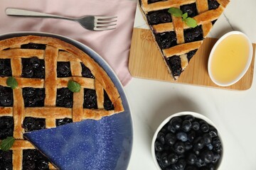 Tasty homemade pie with blueberries, honey and fork on white table, flat lay