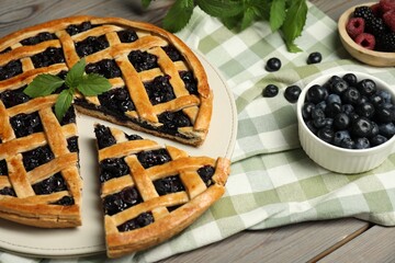 Tasty homemade pie with blueberries, fresh berries and mint on wooden table, closeup