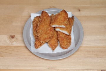 Fried chicken breast are placed on a plate on a wooden table. Fried Chicken, a Healthy Snack.